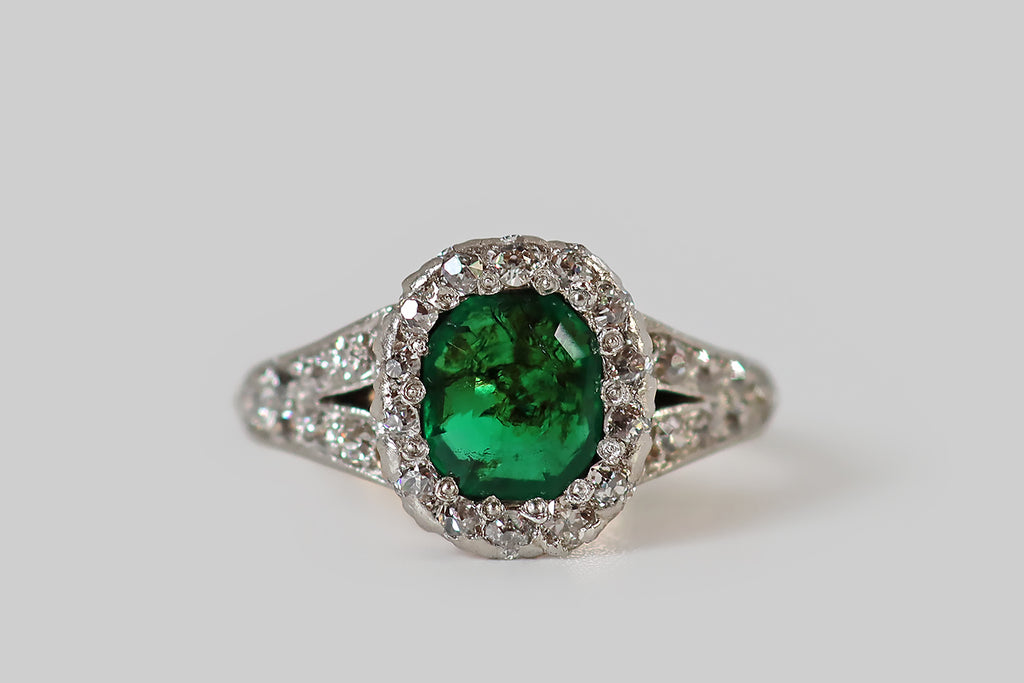 Poor Mouchette | Curated Antique Jewelry, Vintage Jewelry & Engagement Rings | Portland, Oregon | A striking Belle Époque era ring, modeled in 14k rosy yellow gold and platinum, whose primary gem is a natural step-cut emerald, with an especially intense, deep green color! This emerald is faceted in the old style, with a small, low, eight-sided table, and stepped facets that extend from each of its sides.