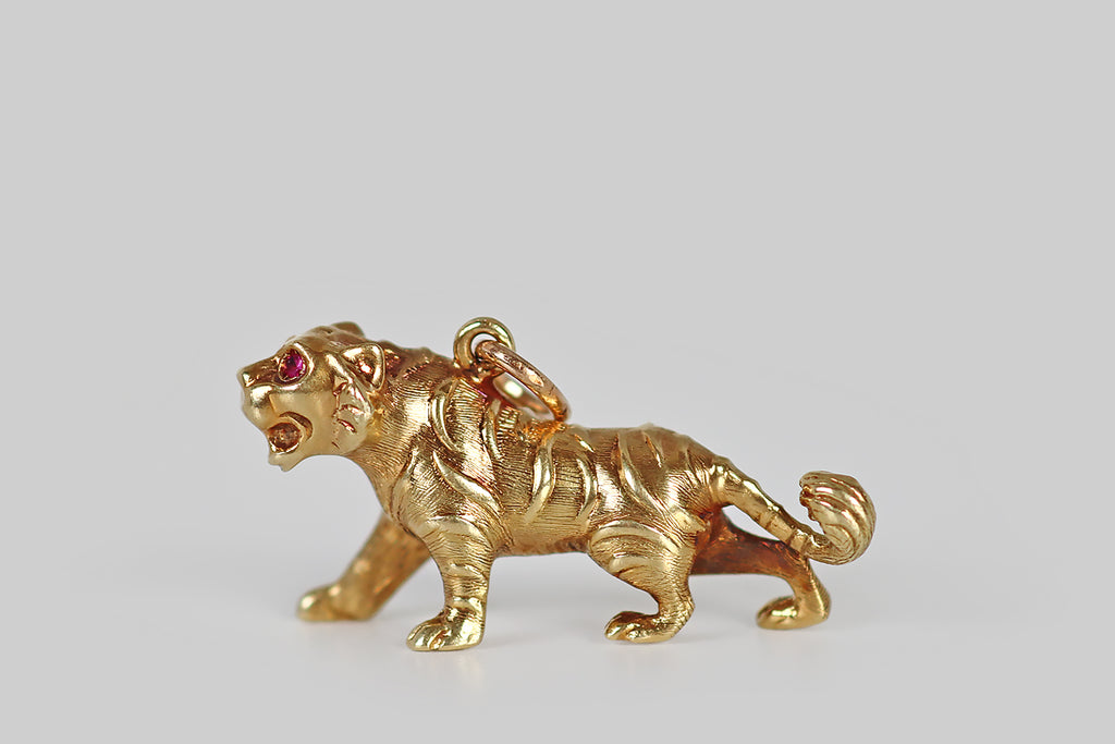 Poor Mouchette | Curated Antique Jewelry, Vintage Jewelry & Engagement Rings | Portland, Oregon | A very cool 1940s pendant, modeled in rosy 14k yellow gold, made to resemble a roaring tiger. This big cat is rendered in a prowling stance— her ears are flattened, her teeth are exposed, and her tail swishes. We love the expressive modeling, here, and the fine details of the tiger's stripes, which are raised slightly, standing above the fine, textured field of her body.