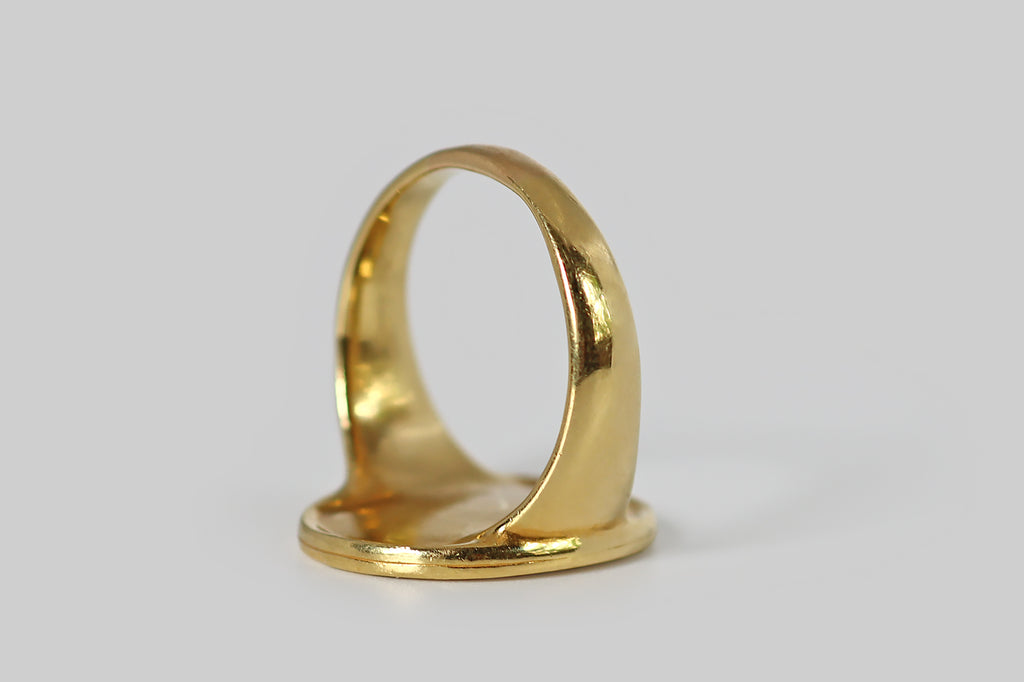 Poor Mouchette | Curated Antique Jewelry, Vintage Jewelry & Engagement Rings | Portland, Oregon | A large vintage signet ring, modeled in 18k yellow gold, whose oval face is decorated with a beautifully-carved, intaglio image of the greek god Zeus. In this rendering, the supreme daddy appears in profile, looking wistful and sensual. His beard is full and wavy; his hair falls in ringlets, below a fillet band. We view him from over a muscular shoulder, as if he were about to turn back