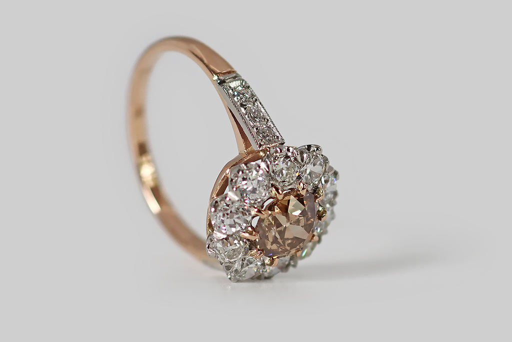 Poor Mouchette | Curated Antique Jewelry, Vintage Jewelry & Engagement Rings | Portland, Oregon | An Edwardian-era, flower-form cluster ring, modeled in 18k rose gold and platinum, whose primary gem is a .90 carat natural, fancy brown, old mine cushion cut diamond. This antique diamond is a beautiful, highly-saturated, peachy-brown color— it is held in ten, tapering rose gold prongs, where it is surrounded by a series of ten white old European cut diamonds.