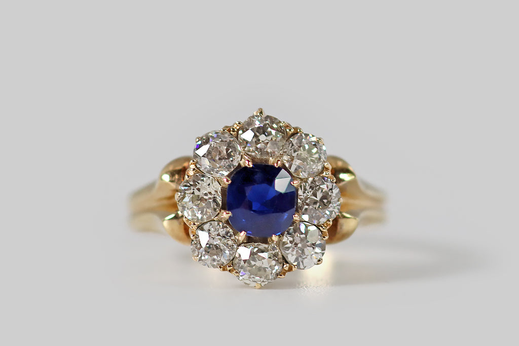 Poor Mouchette | Curated Antique Jewelry, Vintage Jewelry & Engagement Rings | Portland, Oregon | A wonderful, Victorian-era, flower-form cluster ring, modeled in 18k yellow gold, whose primary gem is a natural, old-mine-cushion-cut sapphire. This highly-saturated, deep blue gem is held in tapering prongs, where it is surrounded by a series of eight sparkling, old European cut diamonds (G/H, VS-SI). 