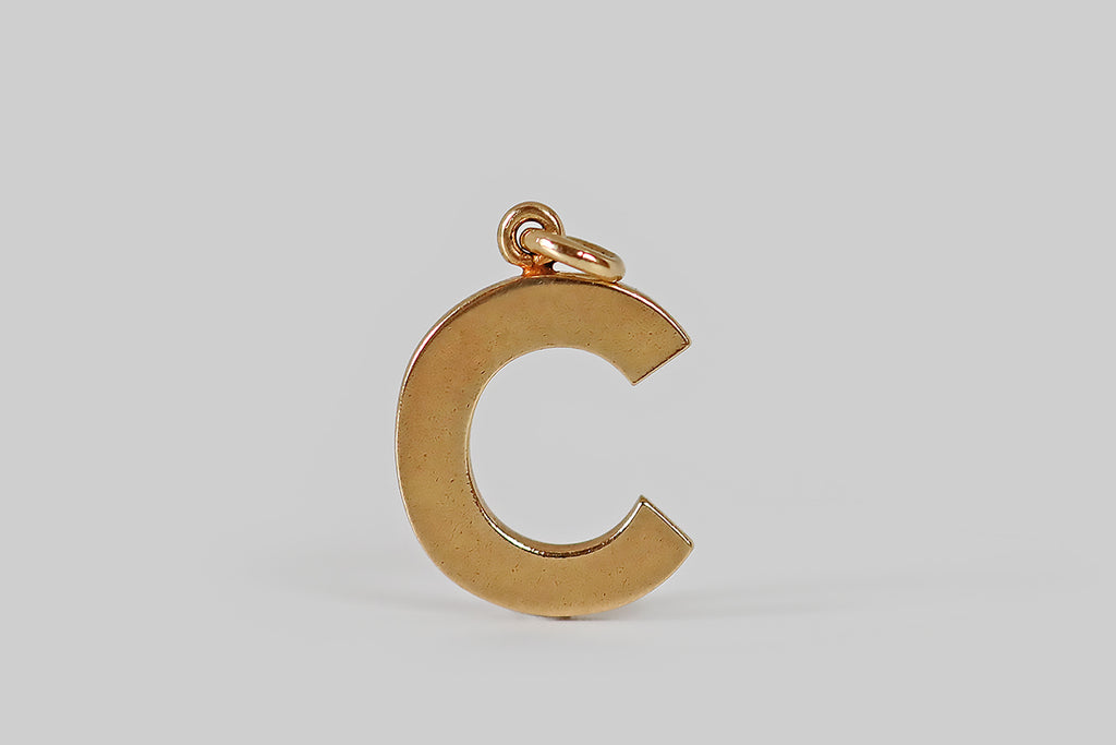 Antique Jewelry Portland, Vintage Jewelry Portland , Antique Engagement Rings | Poor Mouchette | A very cool, vintage letter c charm, modeled in 14k yellow gold. This little "c" is bold and graphic, rendered in blocky, sans serif lettering. Its finish is time-won, buttery and softly matte. A simple loop perches atop the "c," where it hangs from an oval jump ring. We love this chunky little letter 