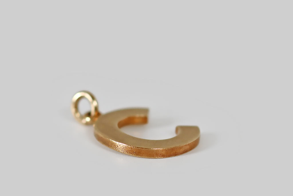 Antique Jewelry Portland, Vintage Jewelry Portland , Antique Engagement Rings | Poor Mouchette | A very cool, vintage letter c charm, modeled in 14k yellow gold. This little "c" is bold and graphic, rendered in blocky, sans serif lettering. Its finish is time-won, buttery and softly matte. A simple loop perches atop the "c," where it hangs from an oval jump ring. We love this chunky little letter